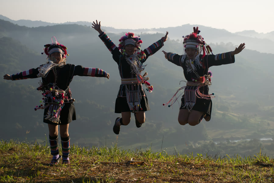 tres personas chinas saltando vestidos con trajes folkloricos